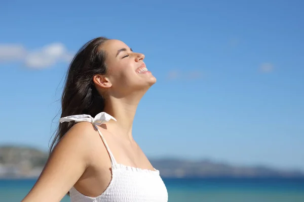 Happy woman in white dress breathing fresh air and laughing on the beach