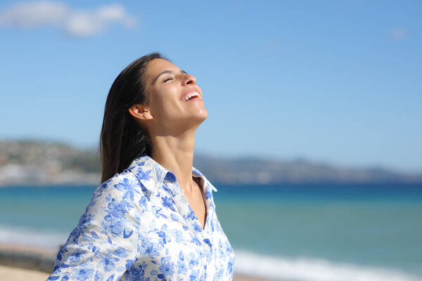Happy woman laughing and breathing fresh air alone on the beach