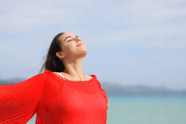 穿着红色呼吸新鲜空气和在海滩上放松的女人 图库照片