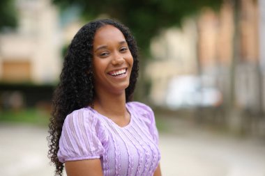 Caddede kameraya bakıp gülen mutlu zenci kadın.