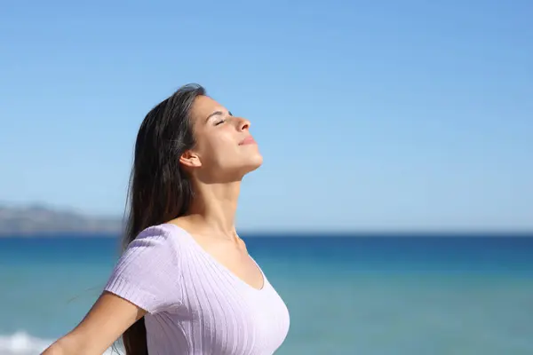 一个在海滩上呼吸新鲜空气和放松的随意女人的简况 免版税图库照片