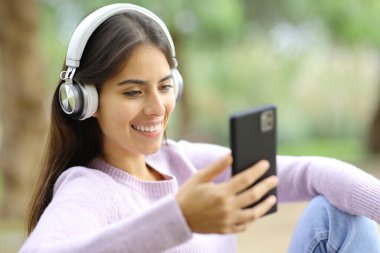 Parkta oturan, kulaklıklı, mutlu Perulu kadın.