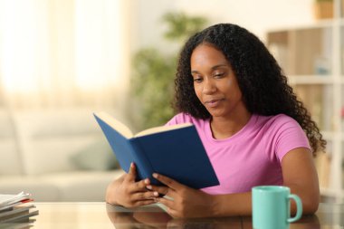 Evinde gazete okuyan siyah bir kadın.