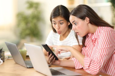 İki şaşkın televizyon çalışanı evde oturup telefon içeriğini izliyorlar.