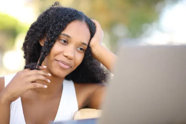 Černá Žena Dotýká Vlasy Flirtování Při Sledování Obsahu Notebooku Venku Stock Snímky