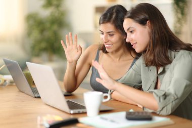 Evde dizüstü bilgisayarla video görüşmesi yapan iki televizyon çalışanı.