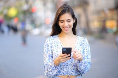 Caddede duran telefonu kullanan mutlu bir kadının portresi.