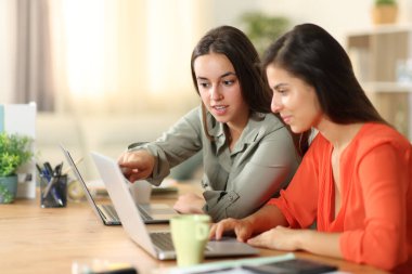 İki televizyon çalışanı evde laptopla konuşup kontrol ediyorlar.