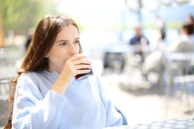 Ciddi bir kadın bar terasında tek başına içki içiyor.