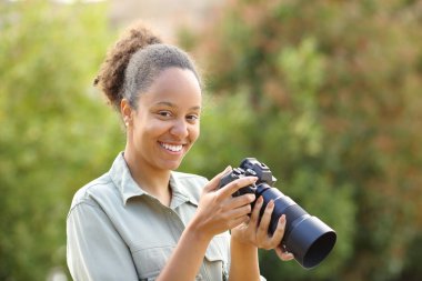 Mutlu siyah fotoğrafçı parktaki kameraya bakar.