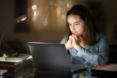 İş kadını gece evde dizüstü bilgisayarı kontrol etmeyi bekliyor.