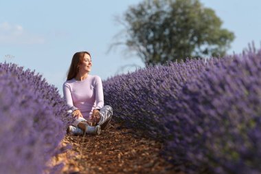 Mutlu kadın lavanta tarlasında oturmuş kafa yoruyor ve dinleniyor.