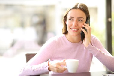 Barda cep telefonuyla konuşan, kahve içen mutlu bir kadın.