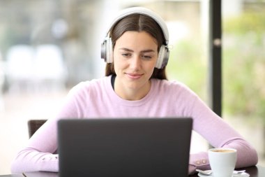 Barda kulaklık takan bir kadının portresi dizüstü bilgisayardan medyayı izliyor.