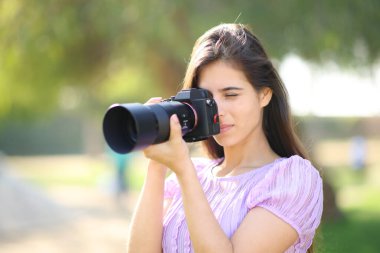 Parkta fotoğraf çeken ciddi bir fotoğrafçı.