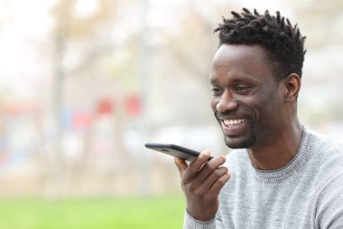 Caddedeki cep telefonundan mesaj yazan mutlu siyah adam.