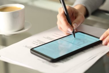 Masa başında akıllı bir telefonla çevrimiçi belge imzalayan bir kadını kapat