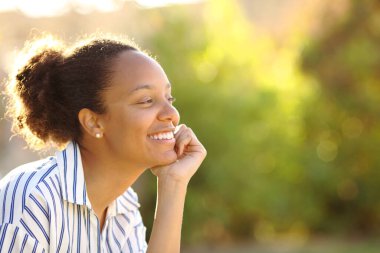 Mutlu siyah kadın yeşil bahçede gülümsüyor.