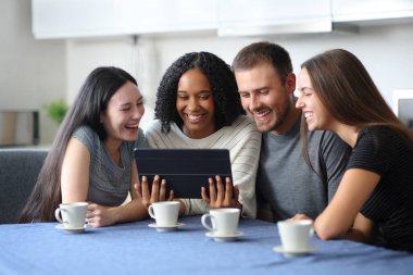 Dört farklı ırktan arkadaş evdeki mutfakta tablette video izliyorlar.