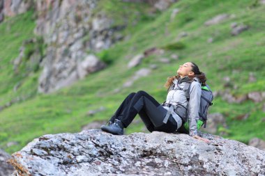 Hiker resting and breathing sitting on a rock in nature clipart