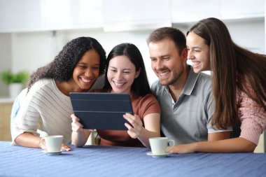 Evdeki mutfakta tablet kullanan dört mutlu ırklar arası arkadaş.