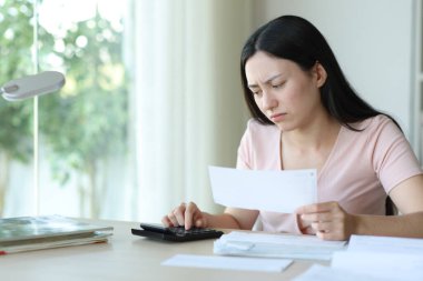 Endişeli Asyalı kadın faturaları evde tutuyor.