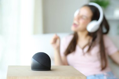 Kulaklık takan bir kadın evdeki akıllı hoparlörle müzik dinliyor.