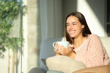 Mutlu kadın içki içiyor ve evdeki bir kanepede oturuyor.