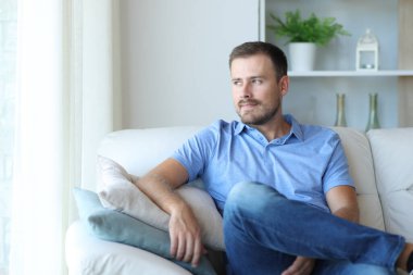 Gururlu bir adam koltukta oturmuş evdeki pencereden bakıyor.