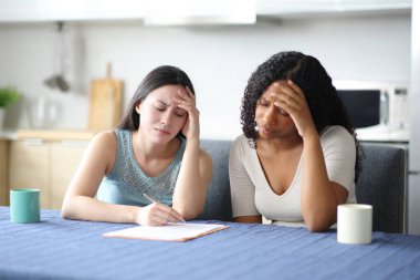 Üzücü ırklar arası arkadaşlar evdeki mutfakta kağıt sözleşmesi okuyorlar.