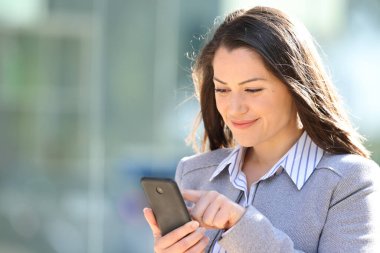 Tatmin olmuş bir yönetici sokakta akıllı telefonları kontrol ediyor.