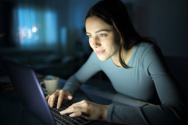 Gece evde dizüstü bilgisayar kullanan güzel bir kadın.