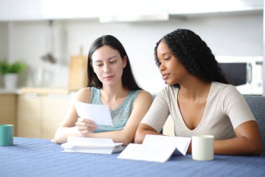 Evdeki mutfakta ırklar arası kadınlar makbuzları kontrol ediyor.