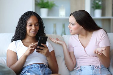 Siyah kadın akıllı telefon kullanıyor, evde arkadaşını görmezden geliyor.