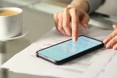 Evdeki ya da ofisteki bir masada akıllı telefon ile çevrimiçi belge imzalayan bir kadını kapat