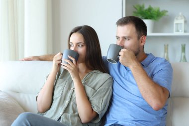 Kahve içen çift evdeki kanepede oturmayı düşünüyor.