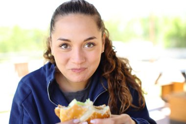 Restoranda hamburger yiyen mutlu bir kadının portresi.