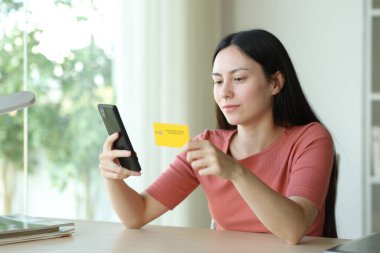 Bir odada telefon ve kredi kartı kullanan Asyalı bir kadın.