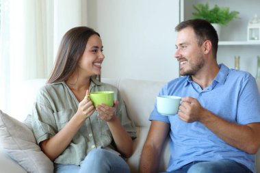 Mutlu çift evdeki kanepede oturup içki içerek konuşuyor.