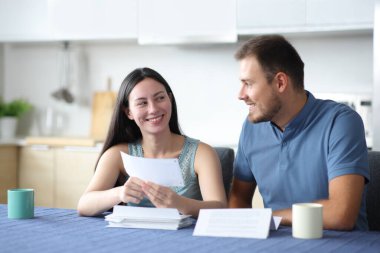 Mutlu ırklar arası çiftler mutfaktaki banka hesap özeti hakkında konuşuyorlar.