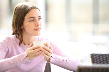 Rahat bir kadın restoranda tek başına kahve içiyor.