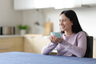 Çay içen Asyalı kadın evde Kitchan 'a bakıyor.