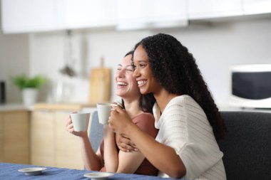 Mutlu ırklar arası bir çift evde kahve içerek gülüyor.