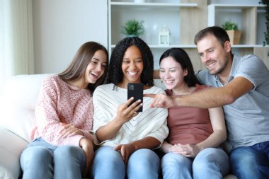 Mutlu bir grup ırklar arası arkadaş telefonda medyayı kontrol ediyor.