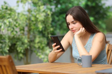 Güneşli bir günde terasta telefon kullanan bir kadın.