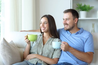 Mutlu çift evde çay içerek kanepede rahatlıyor.