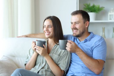 Mutlu çift çay içiyor ve evdeki kanepede oturmaktan zevk alıyor.