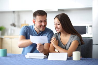 Mutlu çift mutfaktaki banka hesap özeti hakkında konuşuyor.