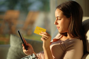 Ciddi bir kadın cep telefonu ve kredi kartıyla internetten satın alıyor.