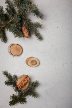 Külahlı mavi köknar ağacı dalı, ahşap kesim ve beyaz ahşap arka planda tarçın çubukları. Noel kartı, kopyalama alanı, dikey çekim